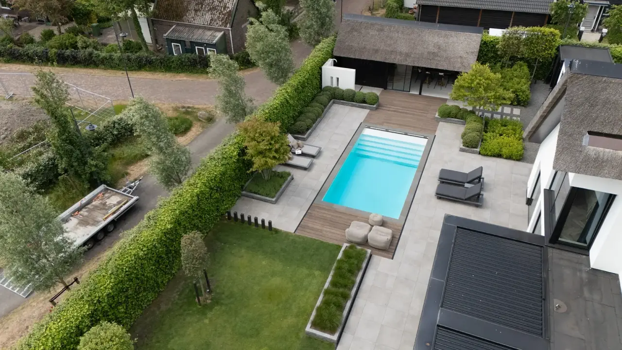Luchtfoto van tuinontwerp met zwembad, terras en modern bijgebouw.