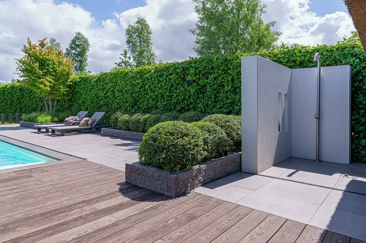 Houten terras met privacy muur en zicht op de rand van het zwembad.