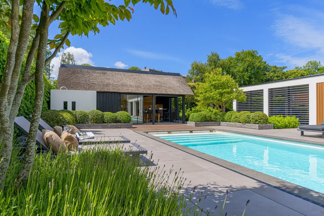 Zwembad aan de tuinzijde met groene beplanting en modern lijnenspel.