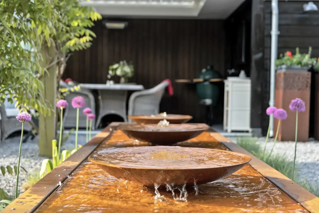 Terras met zitmeubilair aan de rand van de vijver in een sfeervolle tuin.