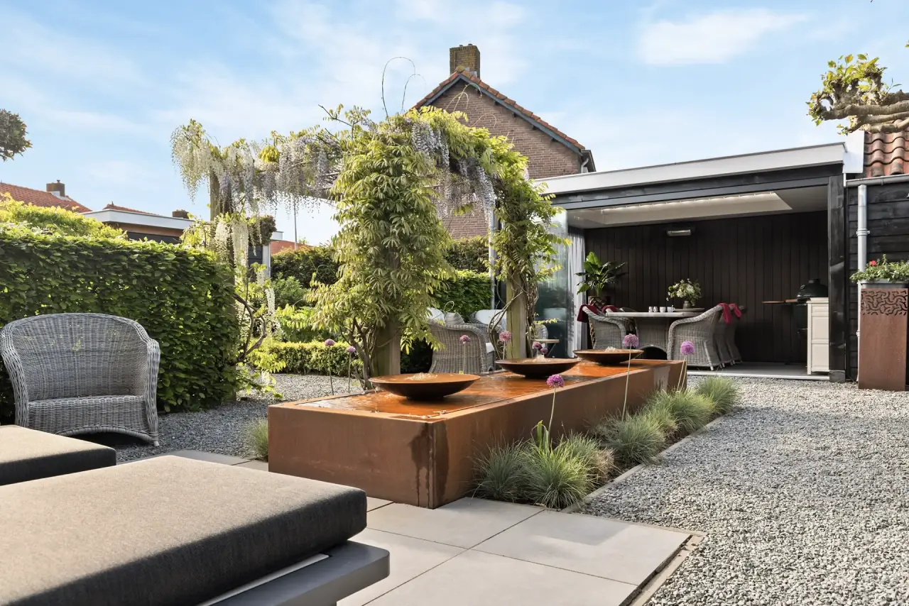 Terras met comfortabele zitplek, beplanting en zicht op het tuinontwerp.