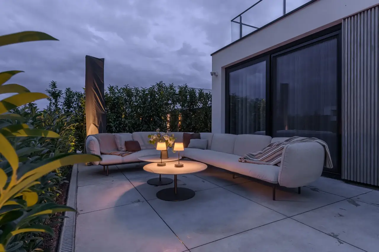 Moderne zithoek met vuurtafel en subtiele verlichting in tuinproject Kamperland