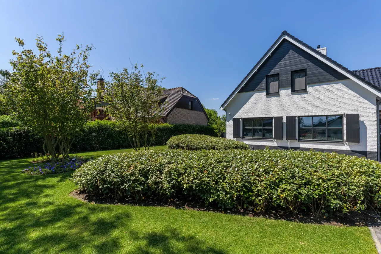 Moderne tuin met tuinkamer en stijlvolle woning met rieten kap in Bruinisse