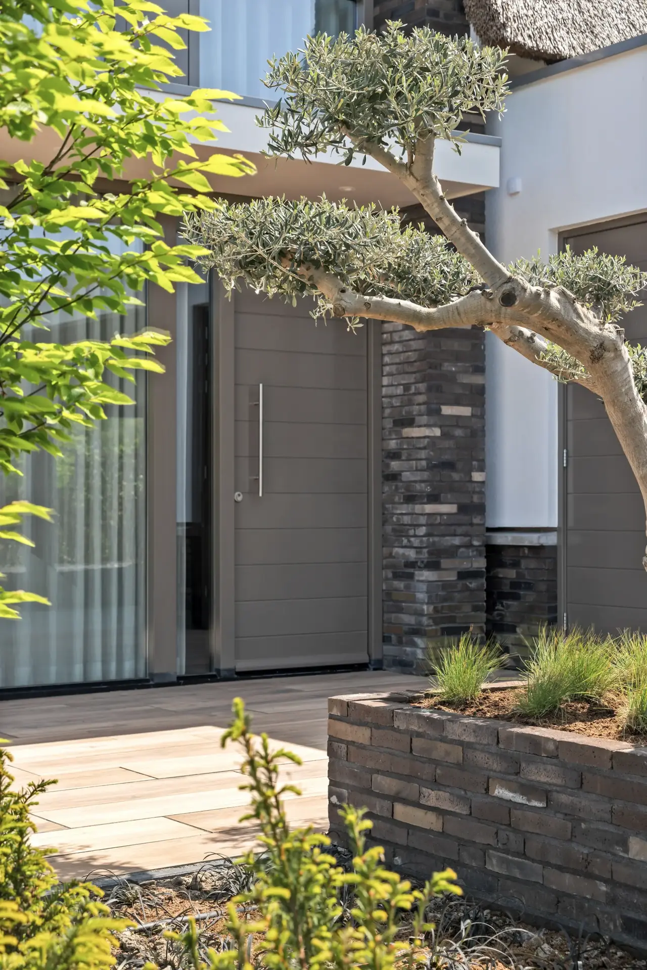 Buitendouche met houten wand en groene beplanting rondom.
