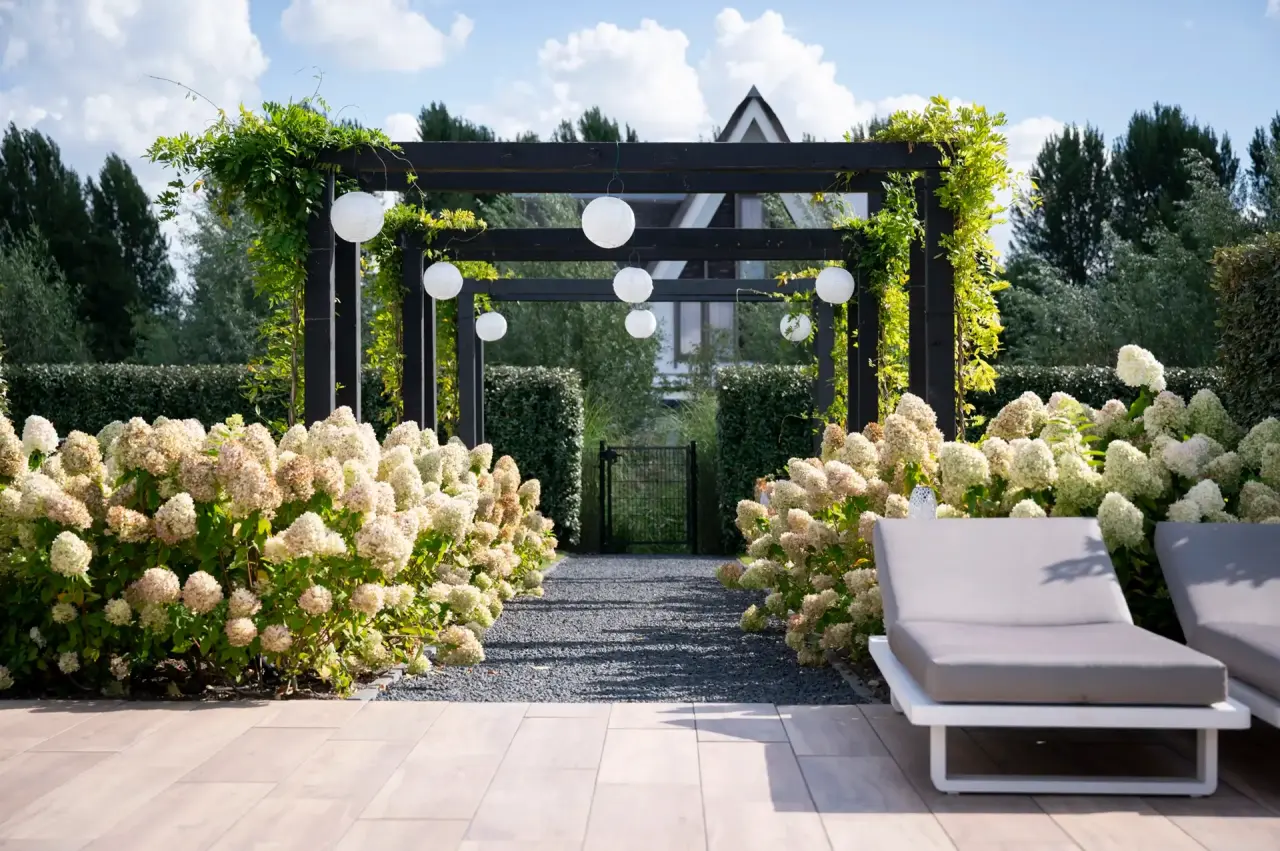 Loungehoek onder de overkapping bij het poolhouse met uitzicht op het zwembad.