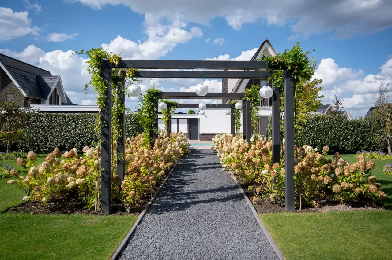 Sierlijke pergola met doorkijk over het pad richting het zwembad.