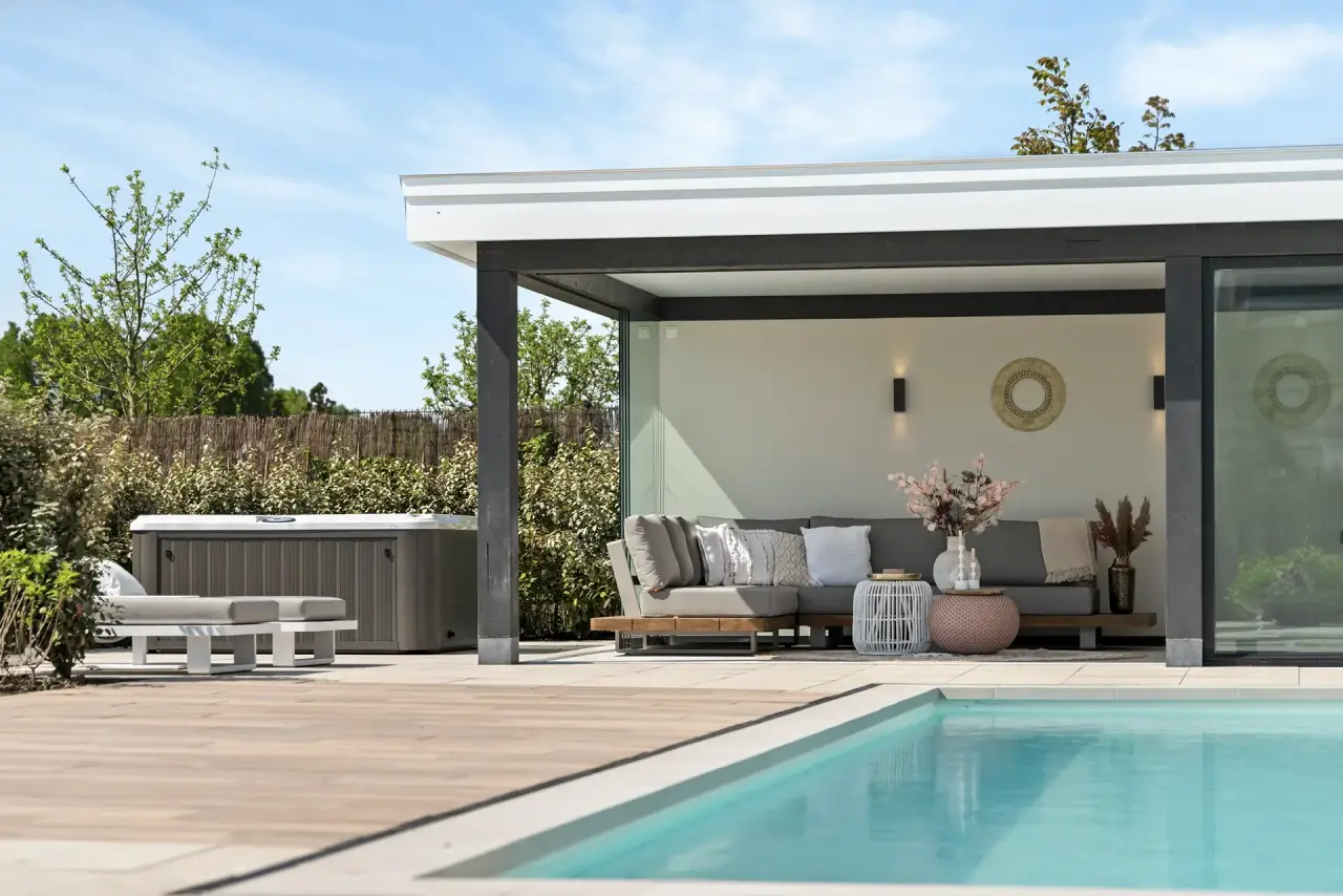 Poolhouse met loungeterras aan het zwembad en uitzicht op de tuin.