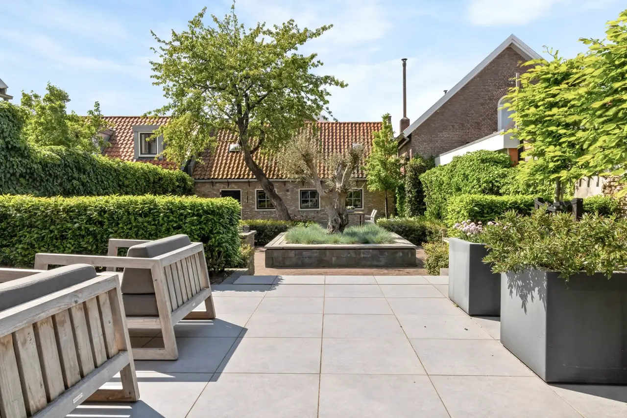 Ruim terras met tuintafel en zicht op de beplante tuinstructuur.