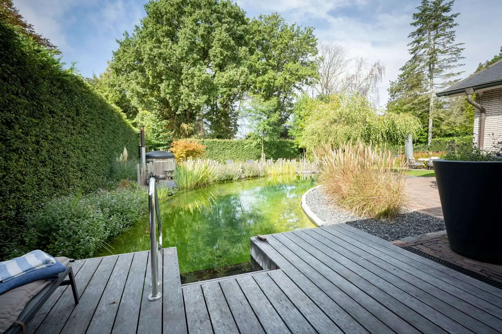 Terras met loungeset en zicht over gazon naar de zwemvijver.
