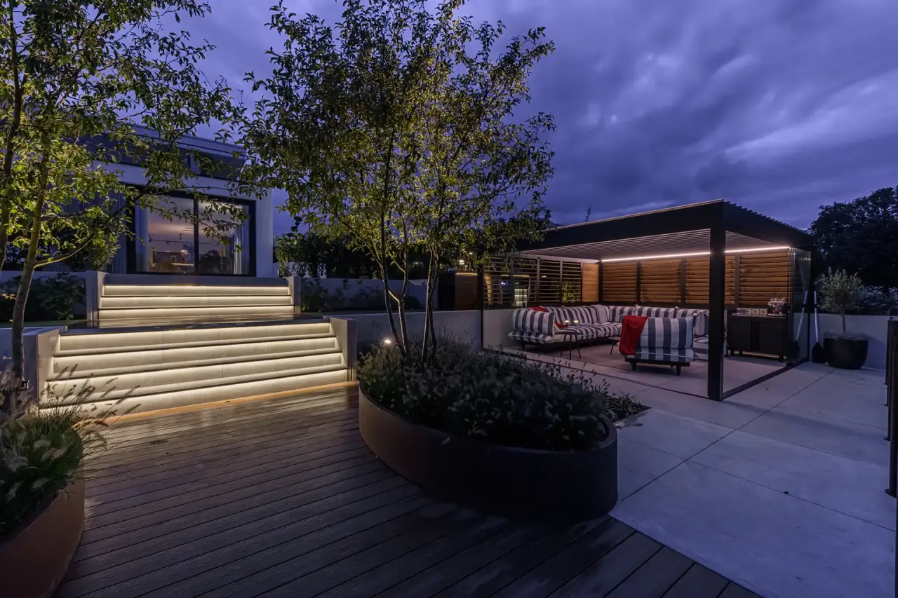 Moderne tuintrap met ge&iuml;ntegreerde verlichting en overkapping in avondlicht