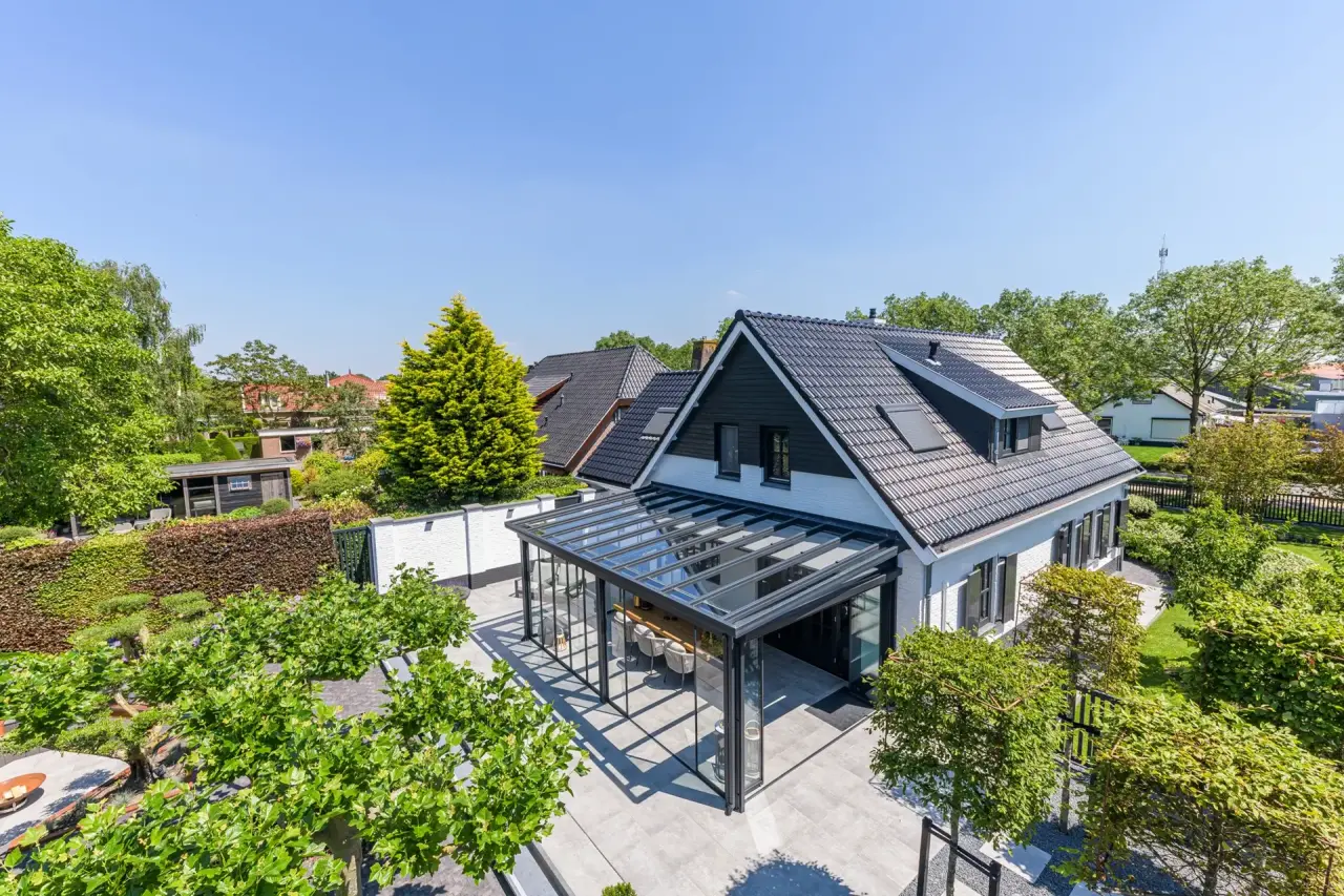Groenrijke tuin met loungehoek en tuinkamer naast woning in Bruinisse