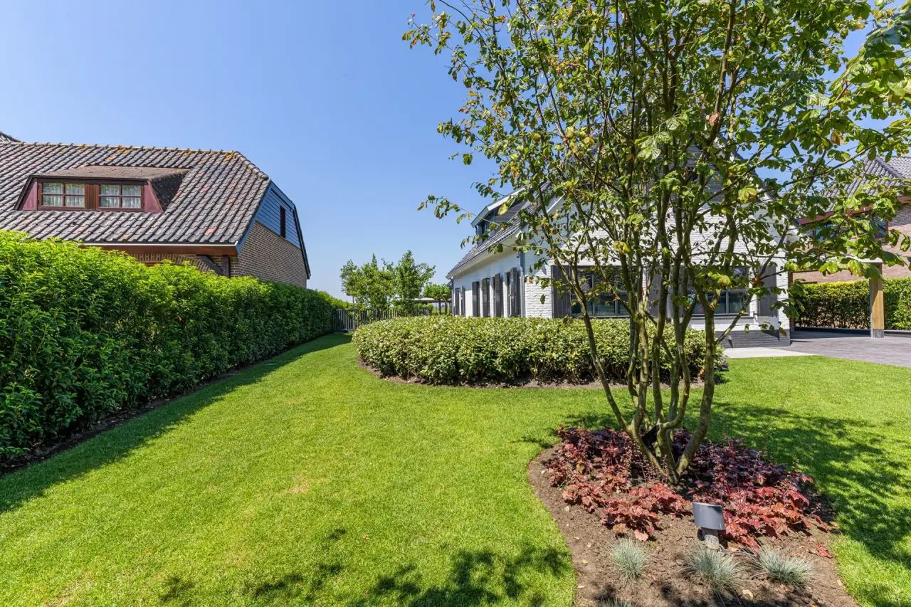Groene voortuin met bloeiende planten en doorkijk naar de woning
