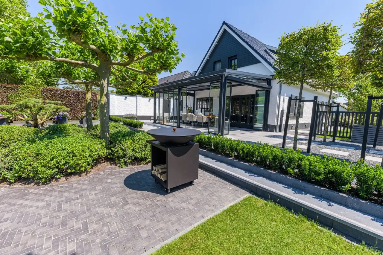 Doorkijk van terras naar moderne tuinkamer tussen bloeiende borders
